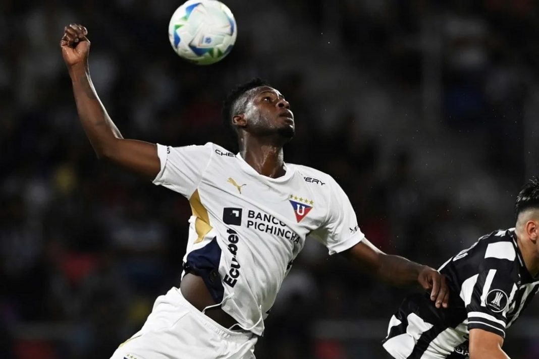 Jugador de LDU Quito disputando una pelota en el aire
